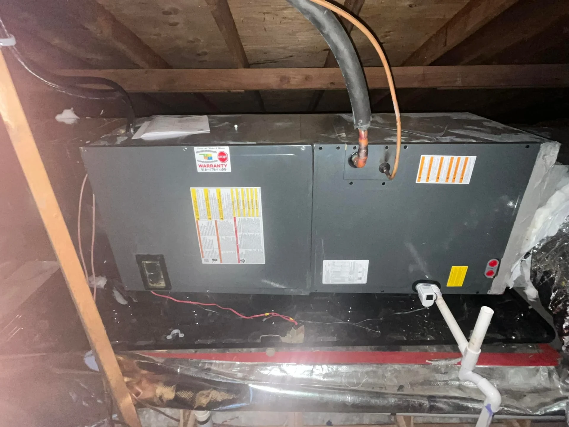 Licensed HVAC technician performing emergency furnace repair on attic unit in Tulsa home